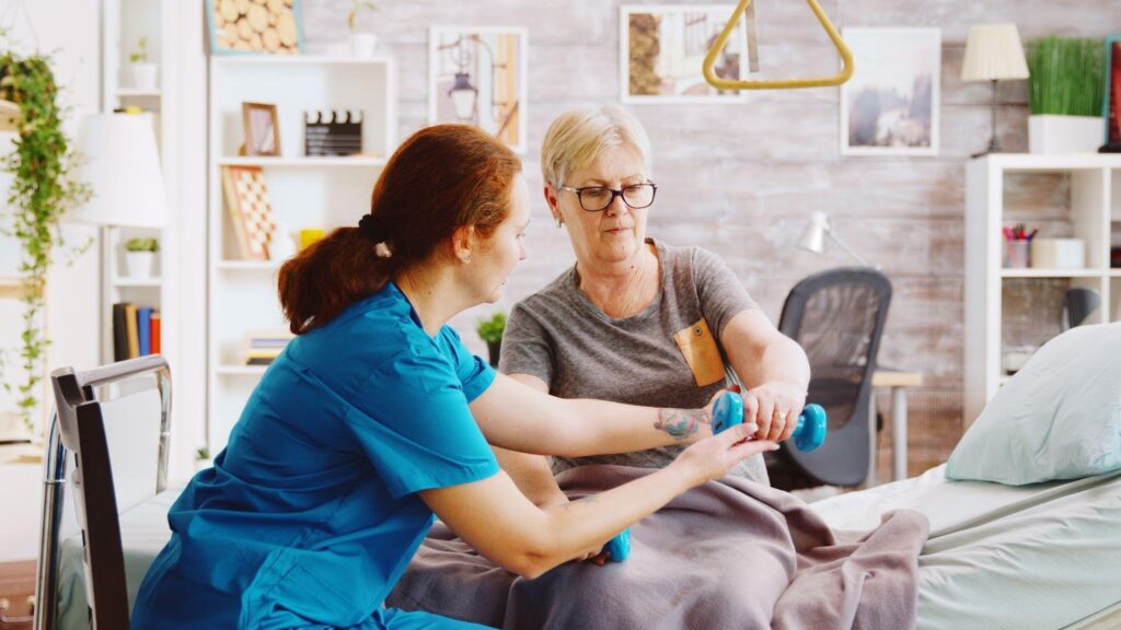 A Healthcare assistant helping an individual lift weights to relieve pain.